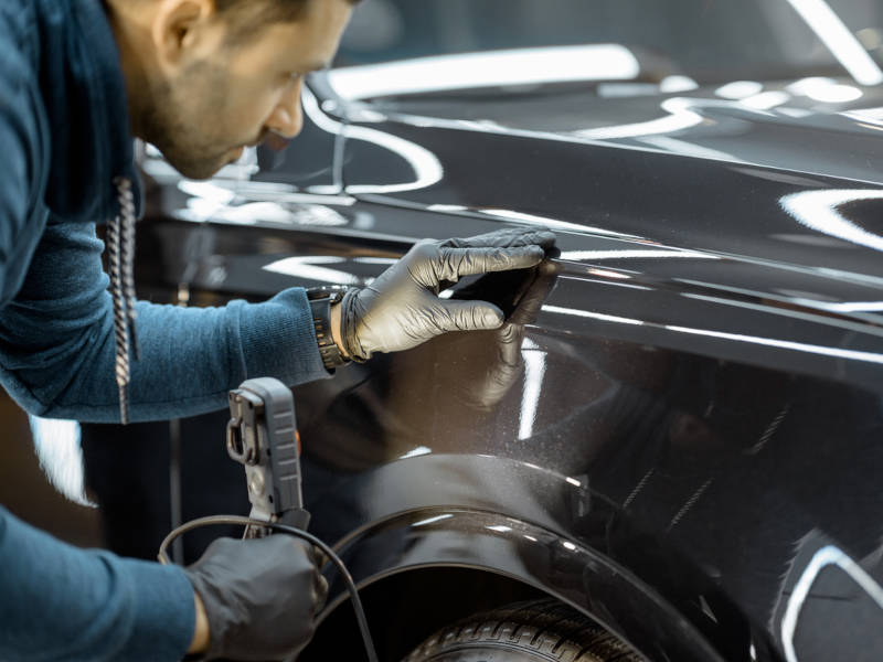 5 corners Isuzu Truck Technician examining vehicle body